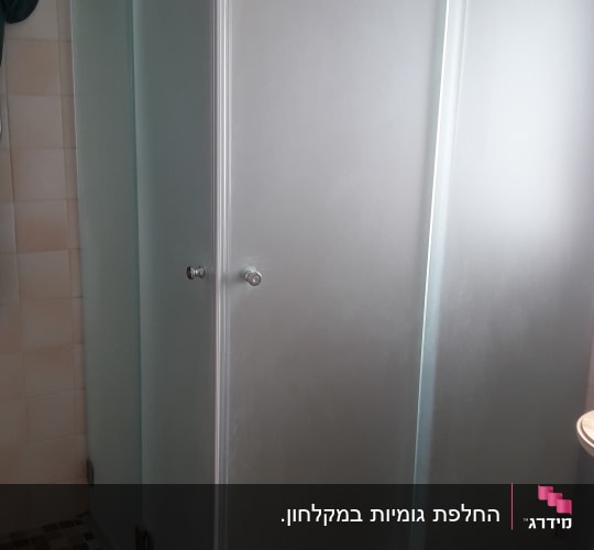 מקלחון פינתי מזכוכית חלבית מותקן בחדר רחצה